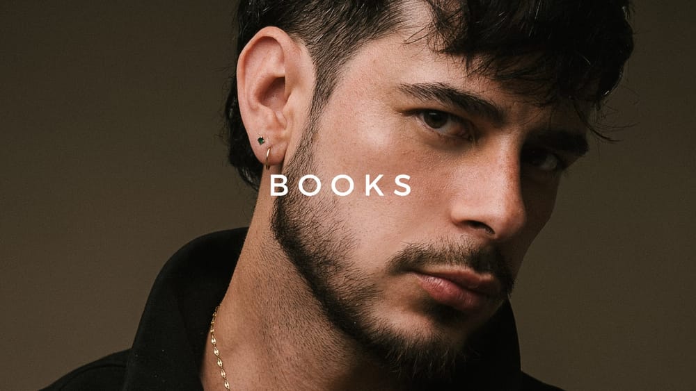 Retrato de un hombre de cabello oscuro y barba, con aros en la oreja, y la palabra BOOKS sobre la imagen
